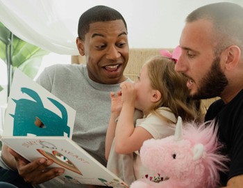 Fathers share a picture book with young child