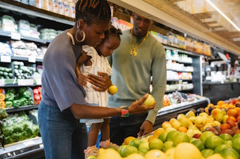 Parents with small child choose fruit in store
