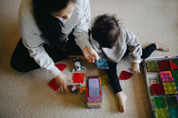 Mother and young child sort objects on carpet