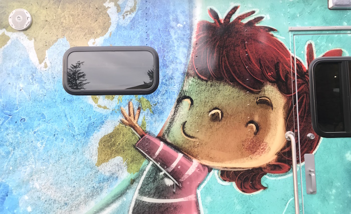 Close up view of illustration of child hugging a giant globe to them