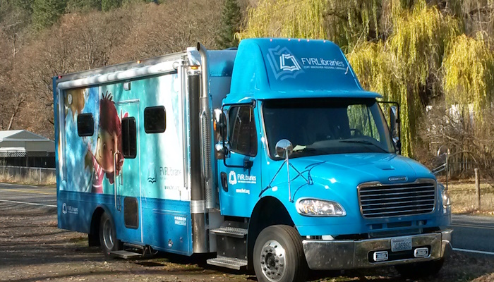 View of the bookmobile at roadside, with yellow-leafed weeping tree in background