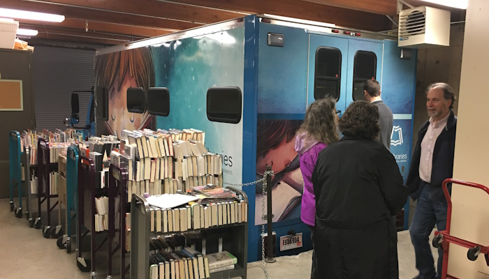 Book carts, heavy with books await staff to load them into the bookmobile in its garage