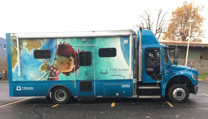 A side view of the bookmobile, featuring an illustration of a child holding up a giant globe