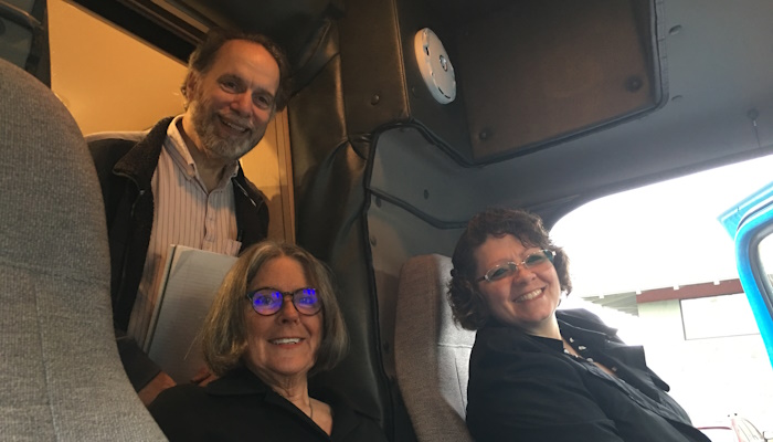 Three staff members smile in the cab on the new bookmobile