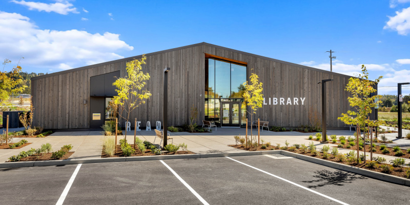 Photo of library building, book return slot on left, door in center, large window on right