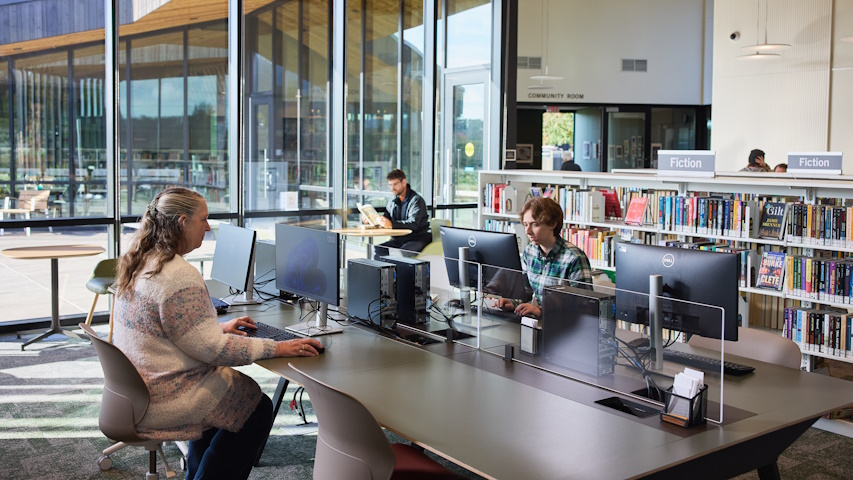 A few people make use of the public computers with the glass walls of the courtyard behind them