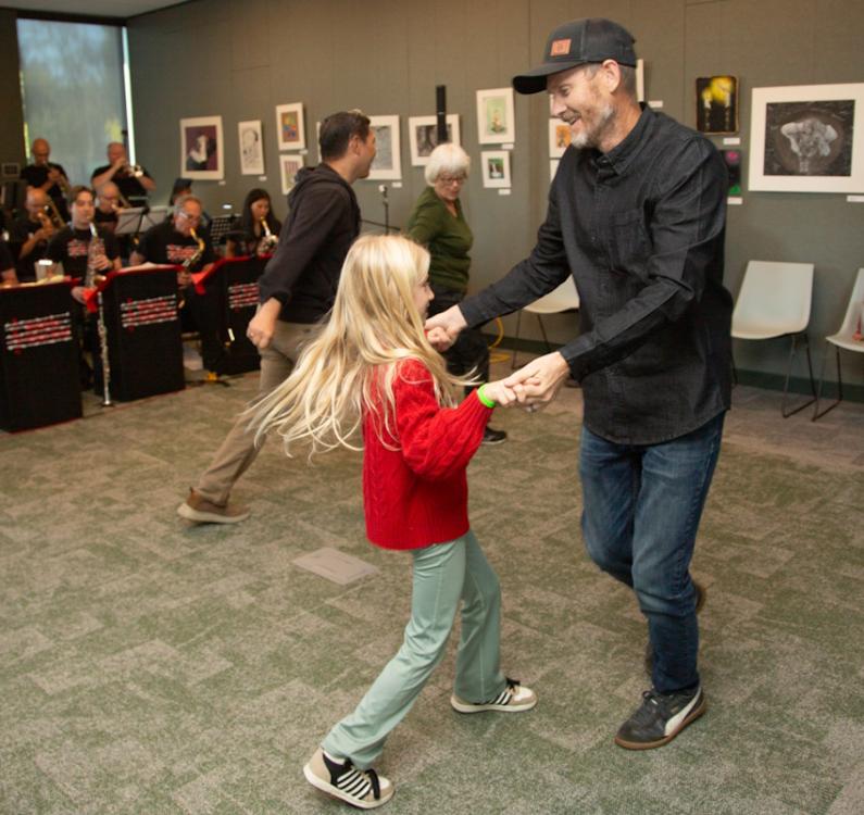 Couples of varying ages dance to a live band inside the Woodland Community library