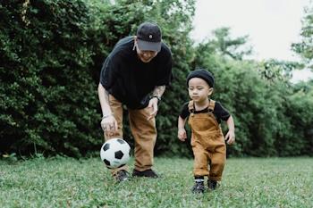 Parent and small child in matching outfits chase soccer ball