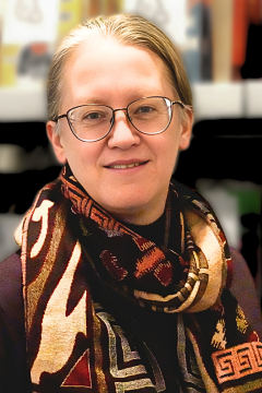 Woman with glasses blonde hair pulled back multi-colored scarf