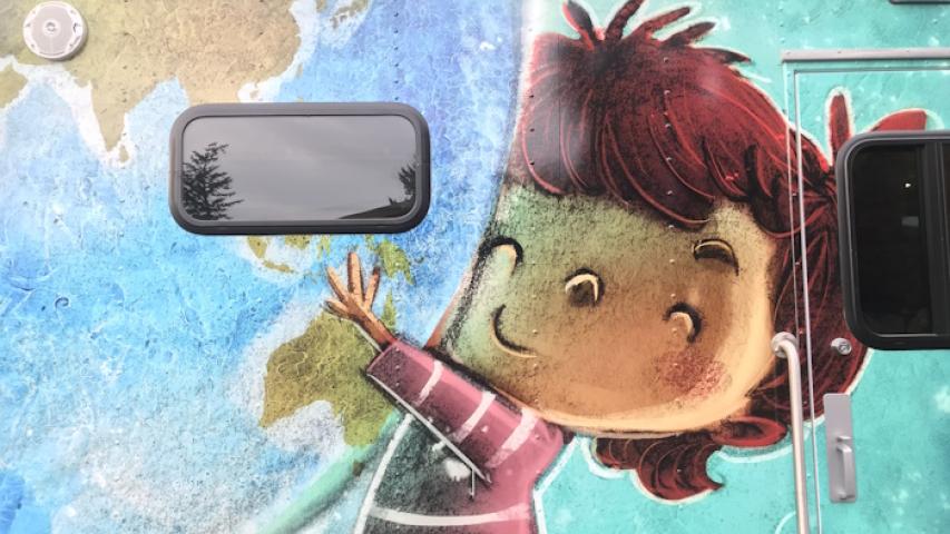 Close up view of illustration of child hugging a giant globe to them