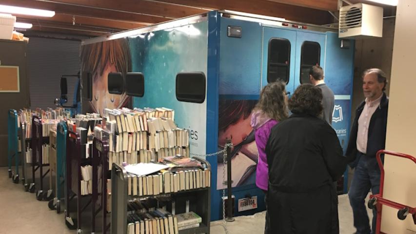 Book carts, heavy with books await staff to load them into the bookmobile in its garage