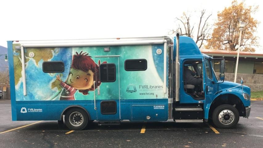 A side view of the bookmobile, featuring an illustration of a child holding up a giant globe